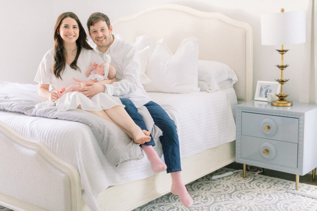 Couple sitting on a bed with newborn baby as an example of favorite baby stores in Atlanta Ga