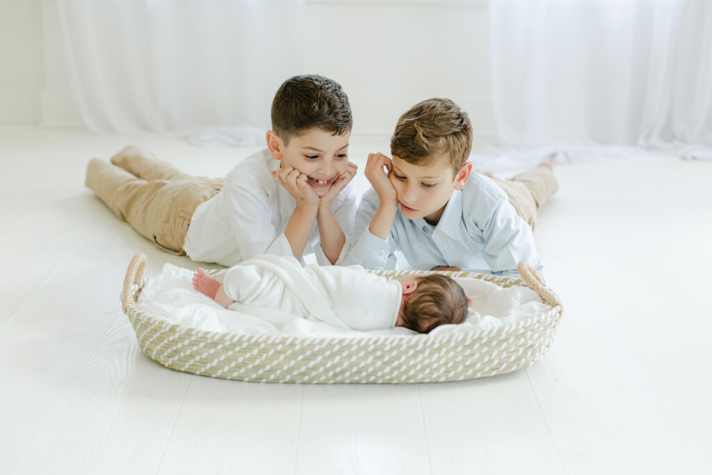 Two boys looking at newborn baby in a basket as an example of favorite baby stores in Atlanta Ga by atlanta newborn photographer